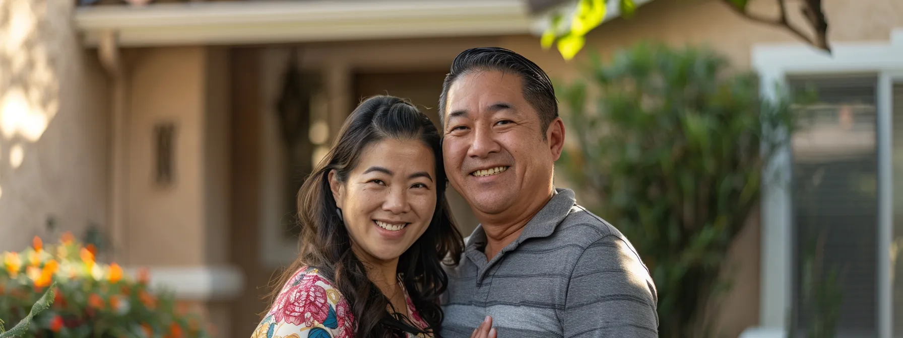 a smiling couple standing in front of a newly purchased house in san diego.