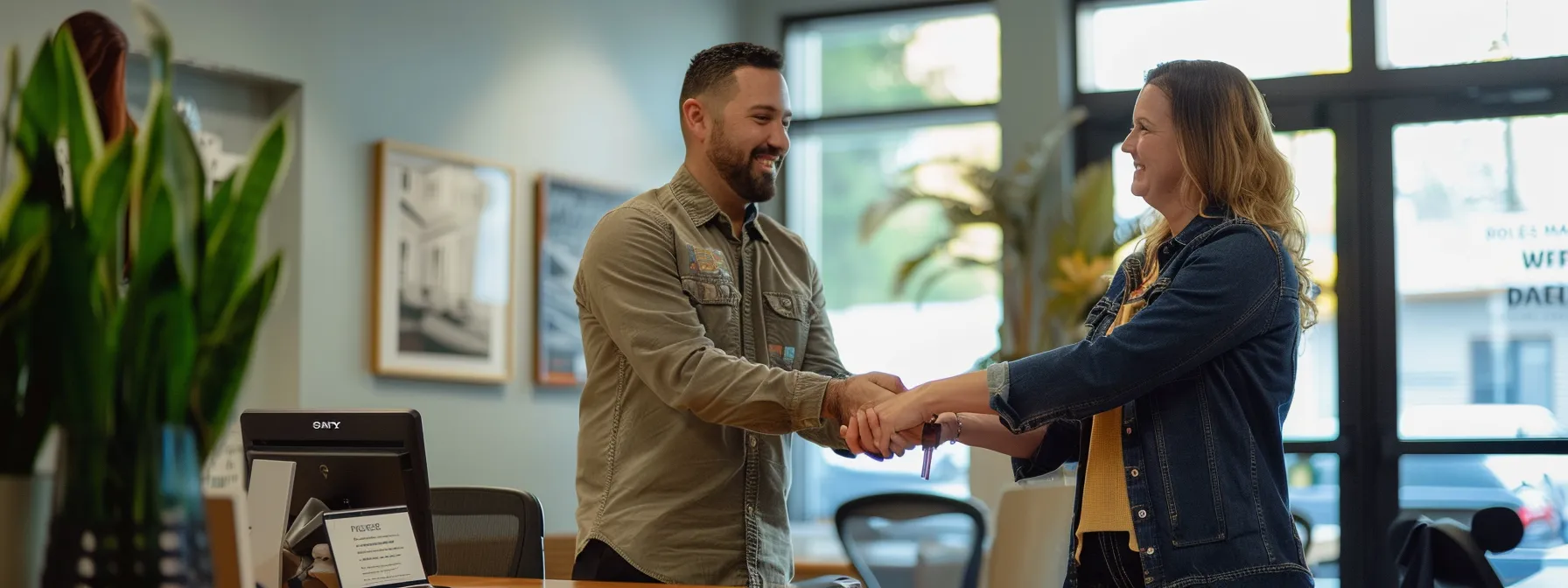 a couple happily receiving the keys to their new home from a loan officer in a bright and welcoming office setting.