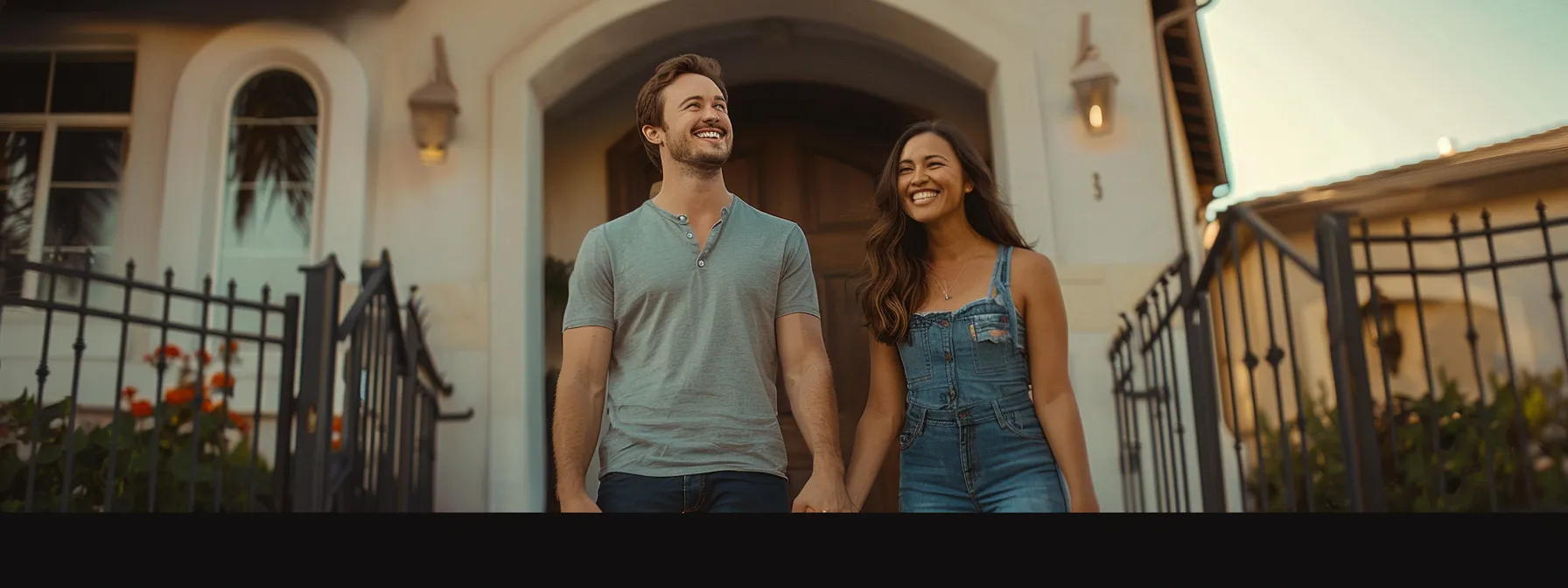 a smiling couple holding hands while standing in front of their newly refinanced home in san diego.