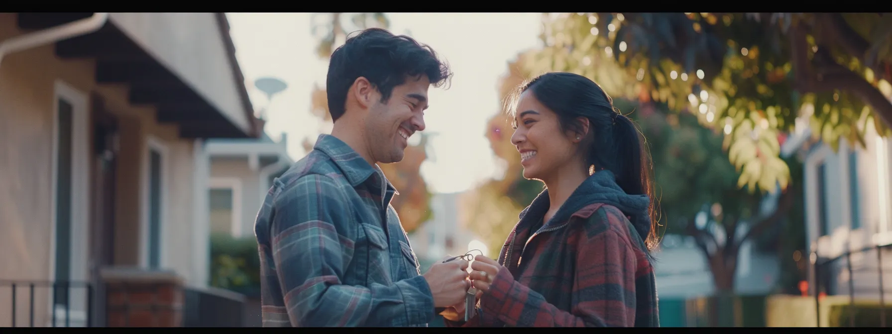 a young couple smiling happily while receiving keys to their new home in san diego.