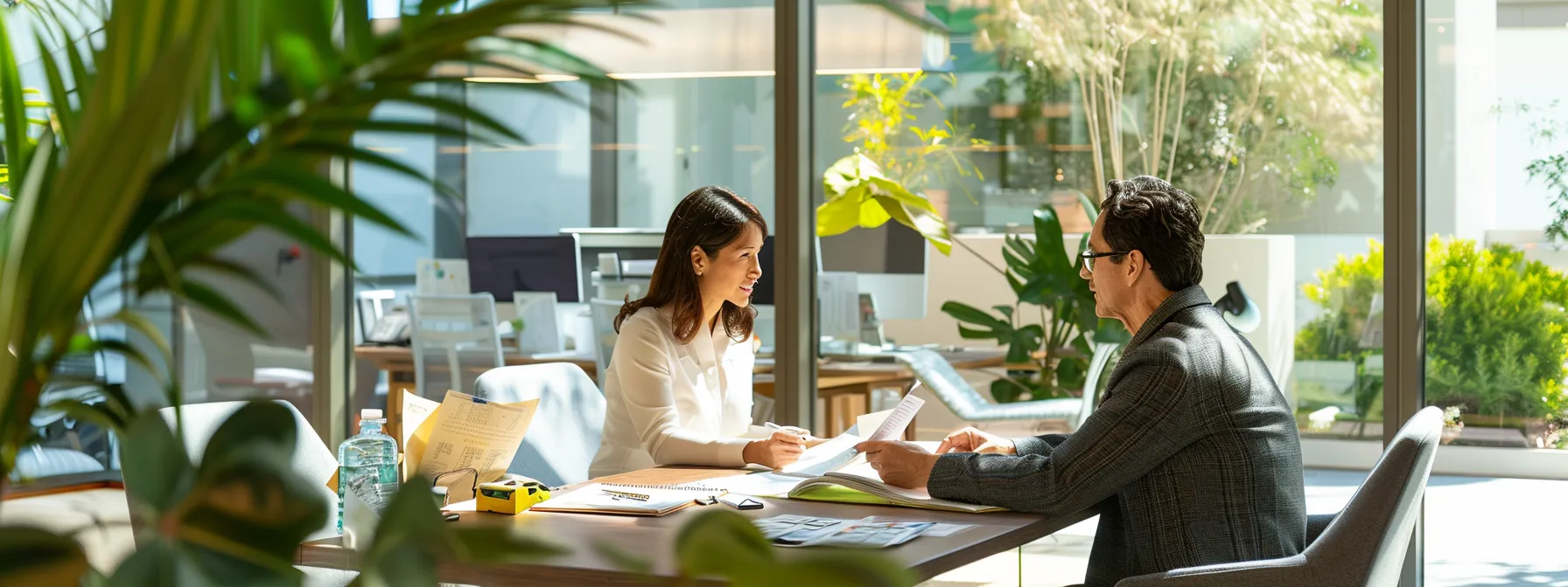 a person reviewing documents and discussing terms with a lender at a desk in a bright office setting.