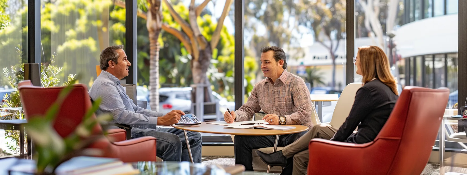 a couple sitting with a mortgage lender, surrounded by paperwork and calculators in a bright san diego office.